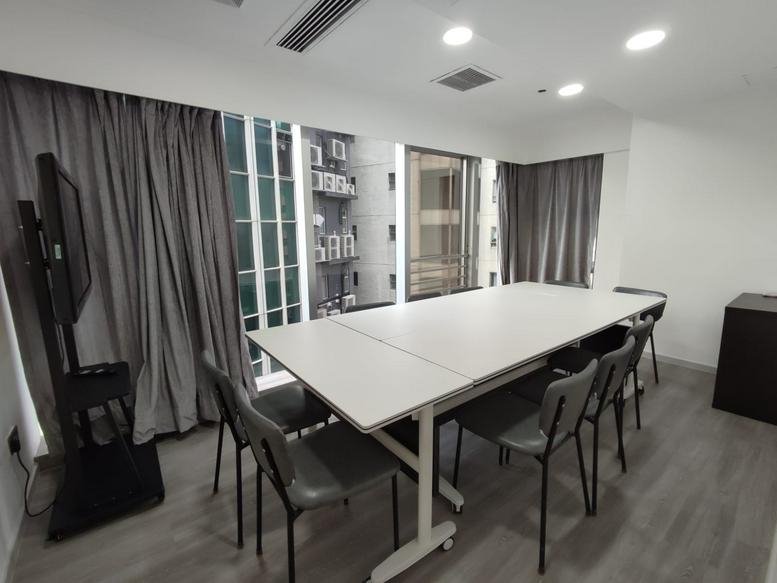 Spacious boardroom at Kyoto Plaza featuring a long white table, gray chairs, and large windows with city views.