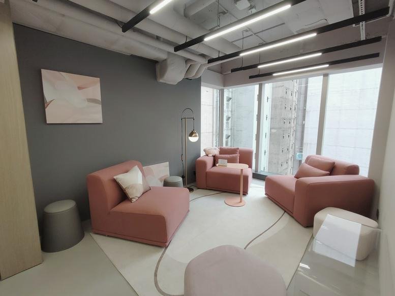 Contemporary breakout space with pink modular seating, a grey accent wall, and designer lighting.
