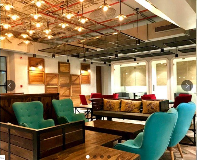 Spacious communal lounge at L3 Sreshta Marvel Sy. No. 136 with teal armchairs and warm hanging lights.