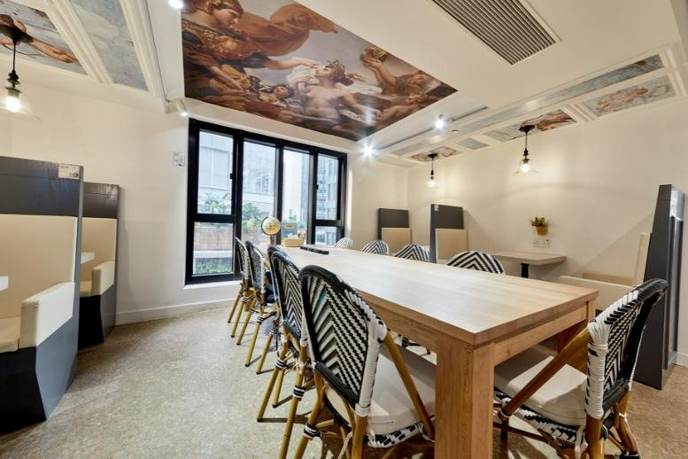 Spacious communal area at L3 World Trust Tower with a long wooden table and ornate ceiling mural.