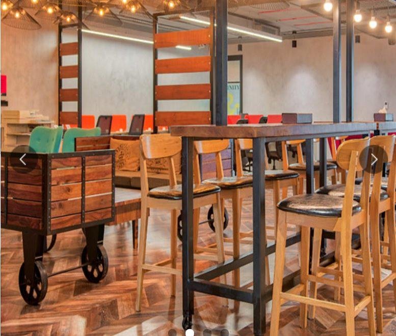 Spacious communal lounge at A3 Godrej Eternia (L7 & L8) with wooden flooring and rustic furniture.