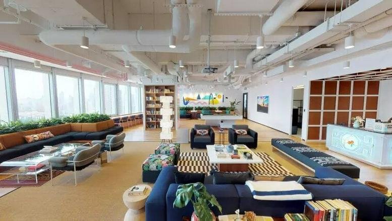 Spacious communal breakout area with comfortable blue sofas and industrial ceilings.