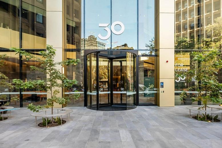 Exterior entrance of M/30, Pirie Street featuring a modern revolving glass door and building logo.