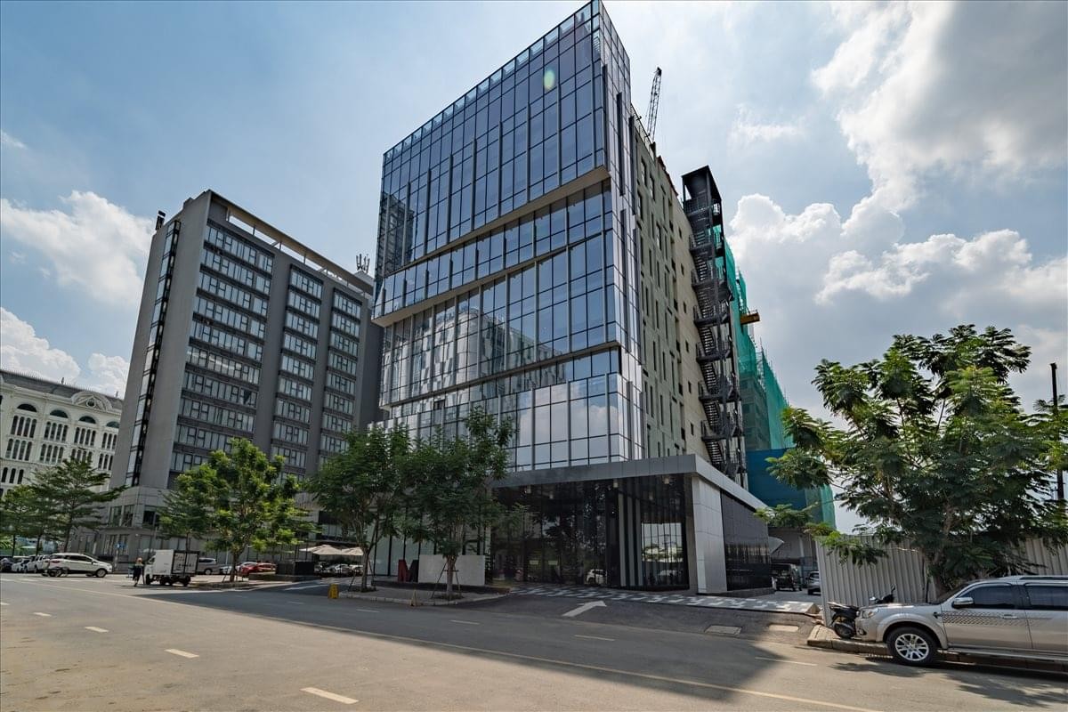 Exterior view of the glass-facade M- Building (4/5F) under a bright sky.