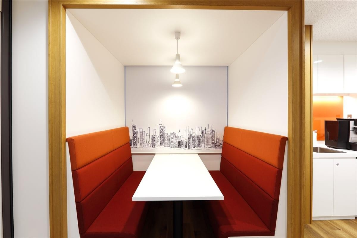 Meeting booth with orange tiered seating and a city skyline mural at Machida, 1-36-2, Morino, Tokyo.