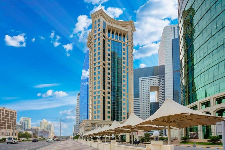 Exterior view of the ornate high-rise facade of the Burj Al Gassar Building under a blue sky.