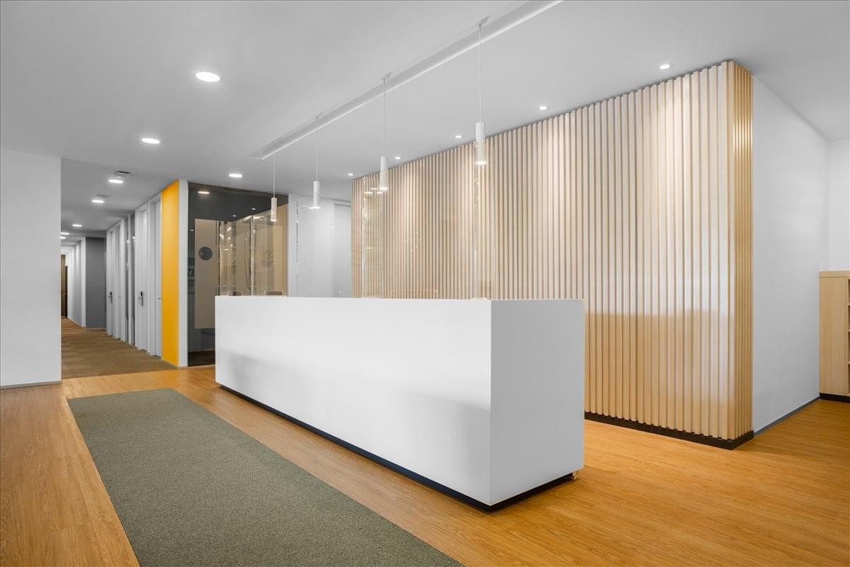 Minimalist white reception desk at the Maslak Orjin Business Centre with light wood paneled walls.