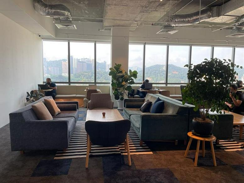 Spacious communal lounge at Menara Ken with plush sofas and large windows overlooking the city.