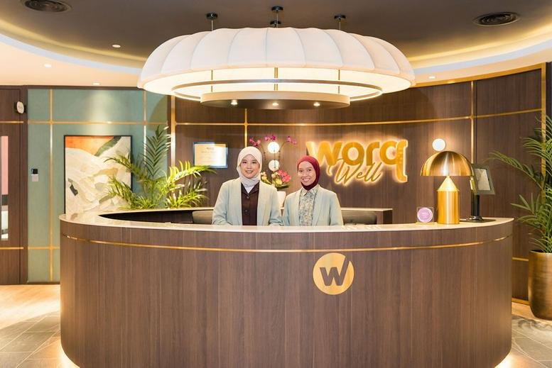 Reception area at Level 2 & 3, Mercu Aspire, KL Eco City, Kuala Lumpur featuring two staff members and warm wood accents.