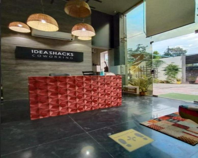 Modern reception area of Ideashacks Coworking featuring a red textured desk and wicker pendant lights.
