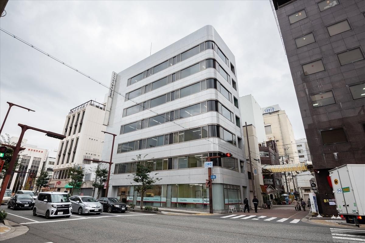 Exterior view of the modern white Mitsuwa Building 1-4F on a city corner.