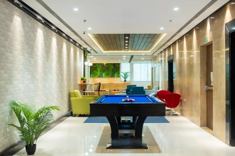 Spacious communal lounge with a pool table and colorful chairs at Modi Business Park.