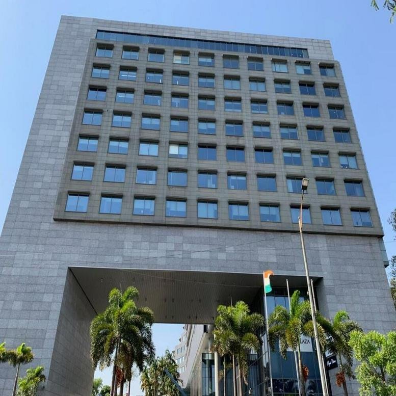 Exterior view of the modern stone-facade Westin Business Plaza building with palm trees at the entrance.