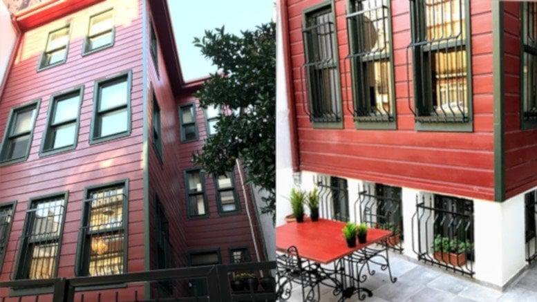 Exterior view of the red wooden facade of the Kamara Altunizade Building with a patio area.