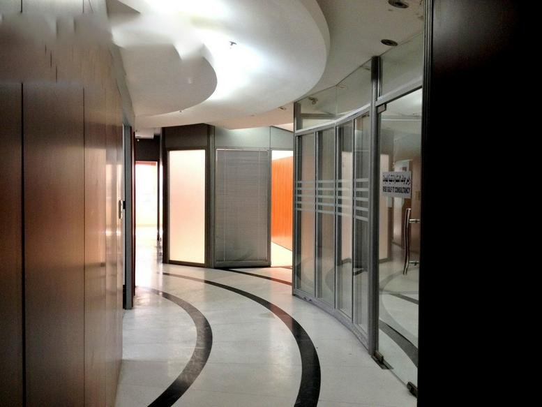 Modern reception area at Muroor road, Abu dhabi featuring curved ceiling lights and glass partitions.