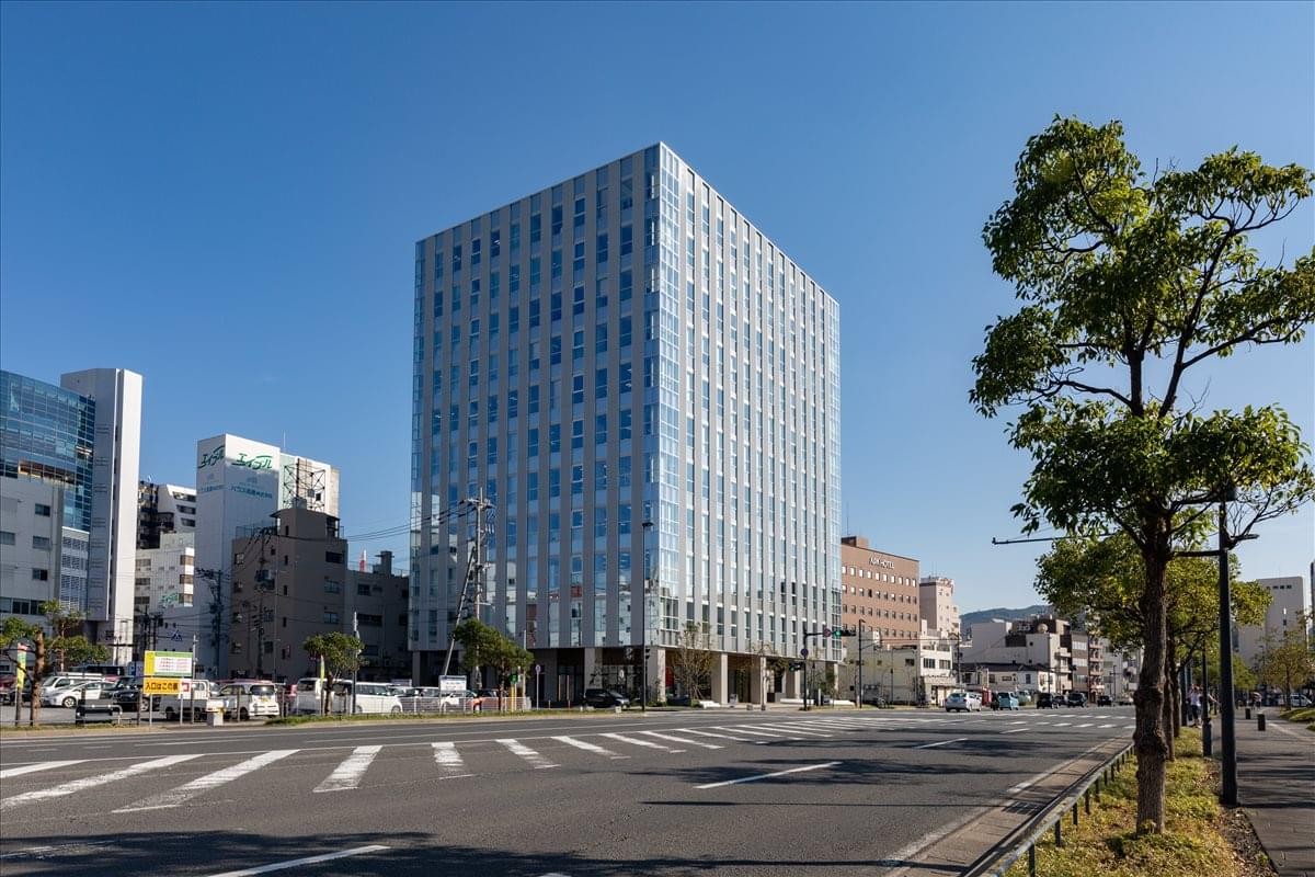 Exterior view of the glass-facade Nagasaki BizPORT building under a clear blue sky.