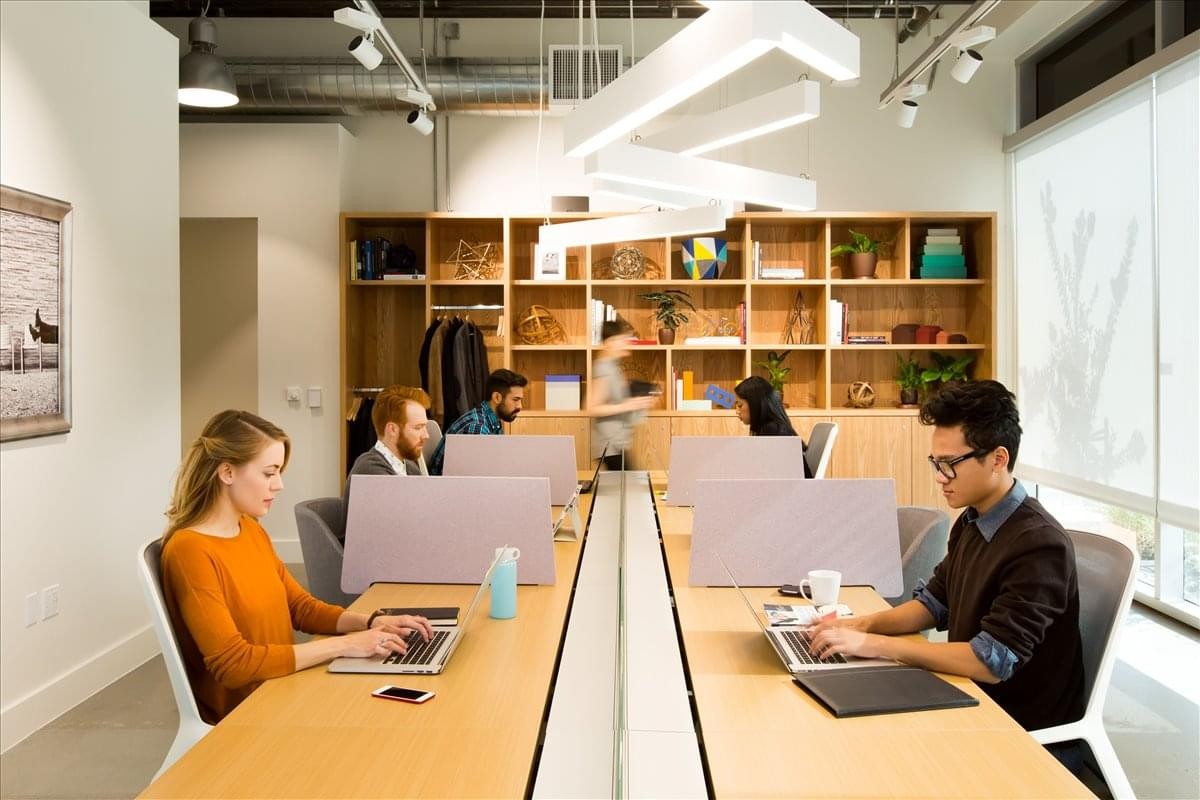 Spacious open-plan workspace at Nippon Life Marunouchi Building with long timber desks and modern lighting.
