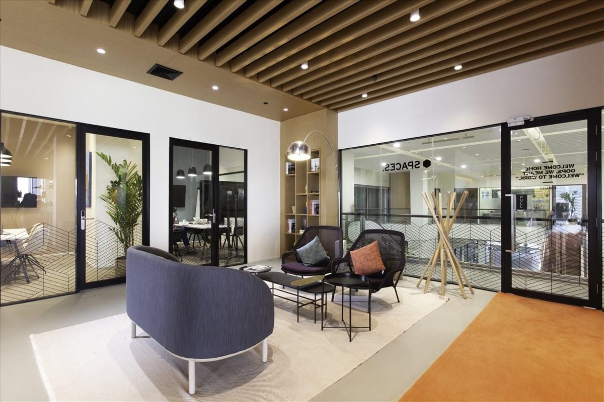 Warm, modern lounge area at 1687/1 Phahonyothin Road with stylish armchairs and timber slat ceiling.