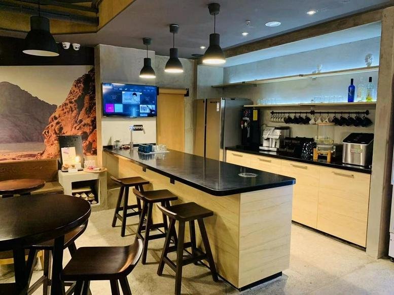 Modern communal kitchen and cafe area at Yishujia Workshop with bar seating and feature mural.