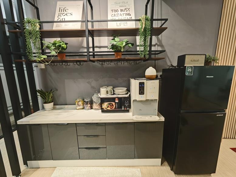 Kitchenette area featuring a grey cabinet, water dispenser, and wall-mounted shelving.