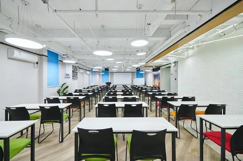 Spacious seminar room at Huaying International Building with rows of white desks and green-accented chairs.