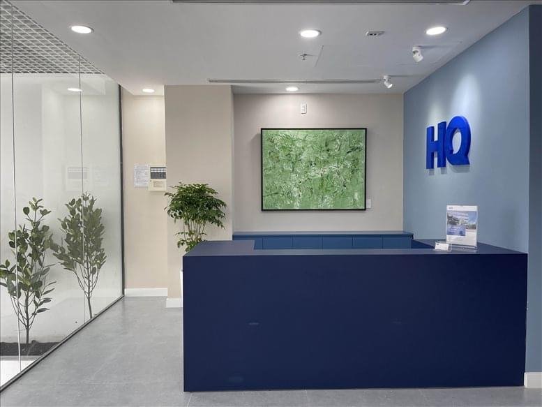 Modern lobby featuring a minimalist blue front desk and a vibrant green botanical artwork.