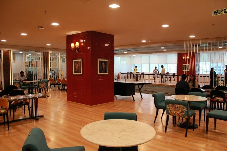 Spacious communal lounge at Infantry Road, Karnataka, Bangalore with a red feature pillar and round tables.