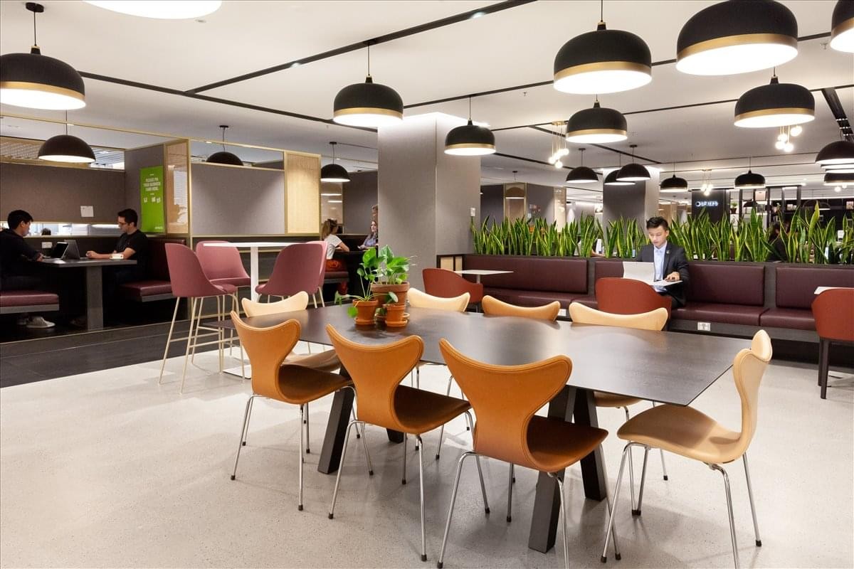 Spacious communal lounge and dining area at Suthi Building featuring warm lighting and modern chairs.
