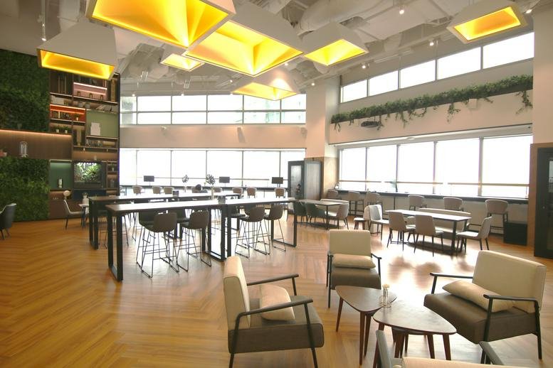 Spacious communal lounge at 79 Anson Road with geometric yellow light fixtures and greenery.