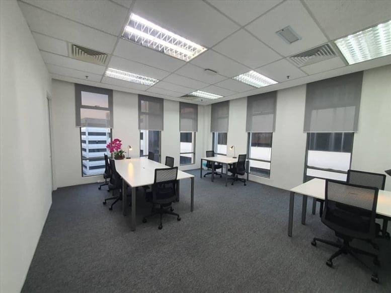 Spacious open-plan workspace with multiple white desks and ergonomic chairs near windows.