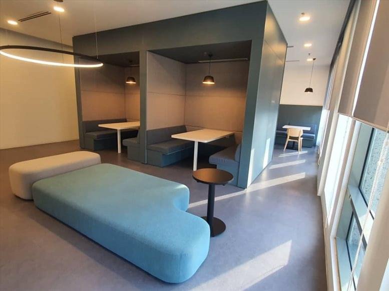 Modern communal lounge with blue modular seating and semi-private dining booths.