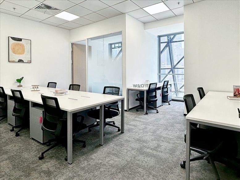 Bright workspace with multiple desks near a large window showing building architecture.