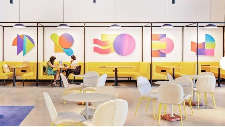 Spacious coworking area at Building 4, North Wing, Nesco IT Park with yellow booths and abstract wall art.