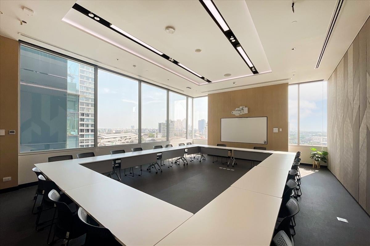 Spacious boardroom featuring a U-shaped white table and panoramic city views.