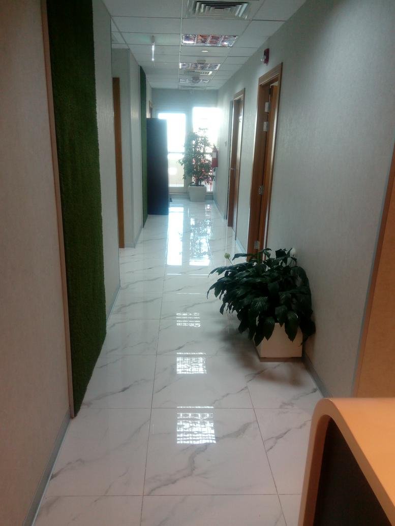 Brightly lit hallway at Al Nazr Plaza with polished marble flooring and a green feature wall.