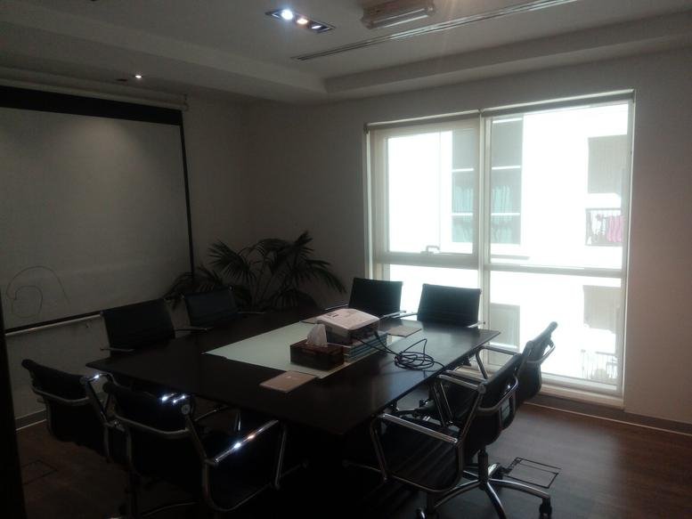 Professional meeting room with a dark wood conference table and black mesh chairs.