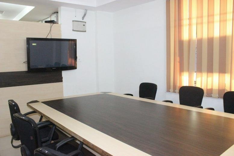 Spacious boardroom at Rio Mall with a large dark wood table and wall-mounted television.