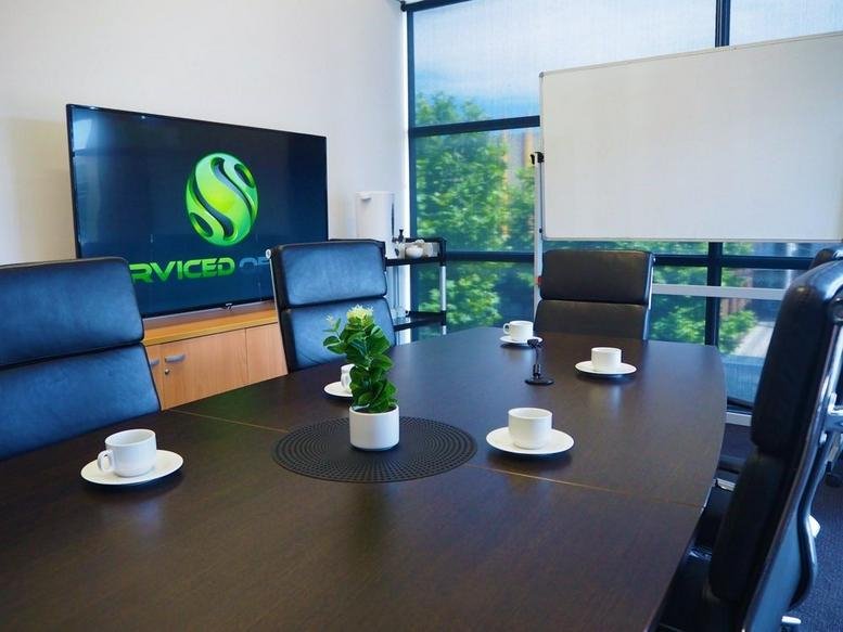 Meeting room at C5, Level 1, 2 Main Street featuring a dark wood table, leather chairs, and a monitor.