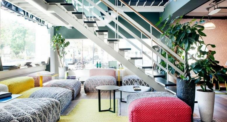 Colorful breakout lounge at 1-1-29, Daimyo 1 Chome with patterned seating and plants under a staircase.