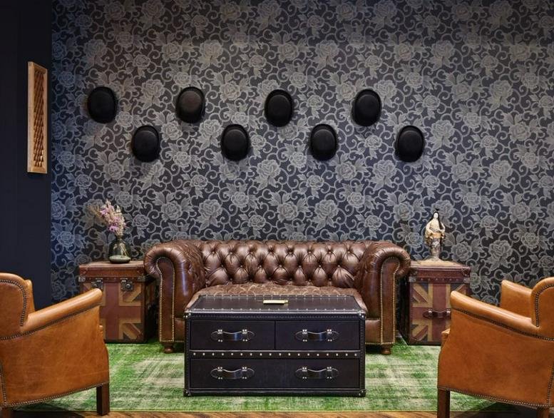 Sophisticated lounge at 1-5-8, Jingumae, Tokyo with a leather sofa, top hats on wallpaper, and a trunk coffee table.