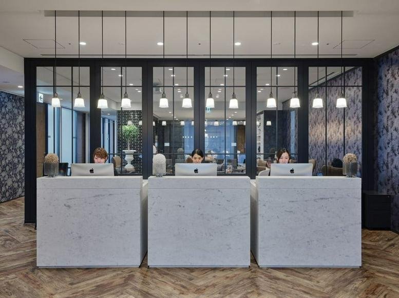 Reception area at 1-5-8, Jingumae, Tokyo featuring marble desks and modern pendant lighting.