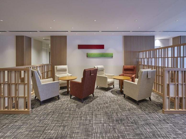 Lounge area at AREA Shinagawa Building with leather armchairs and wooden partitions.