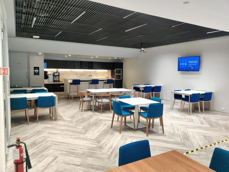 Spacious modern communal lounge at Canberra, UB City, 24 Vittal Mallya Road with blue chairs and wood-look flooring.