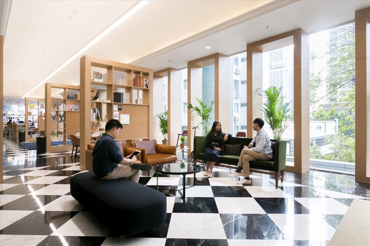 Spacious communal lounge with checkered flooring, stylish seating areas, and tall windows.