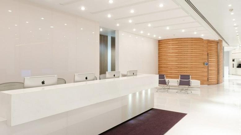 Bright white reception area with a long sleek desk and wood-slat feature wall.