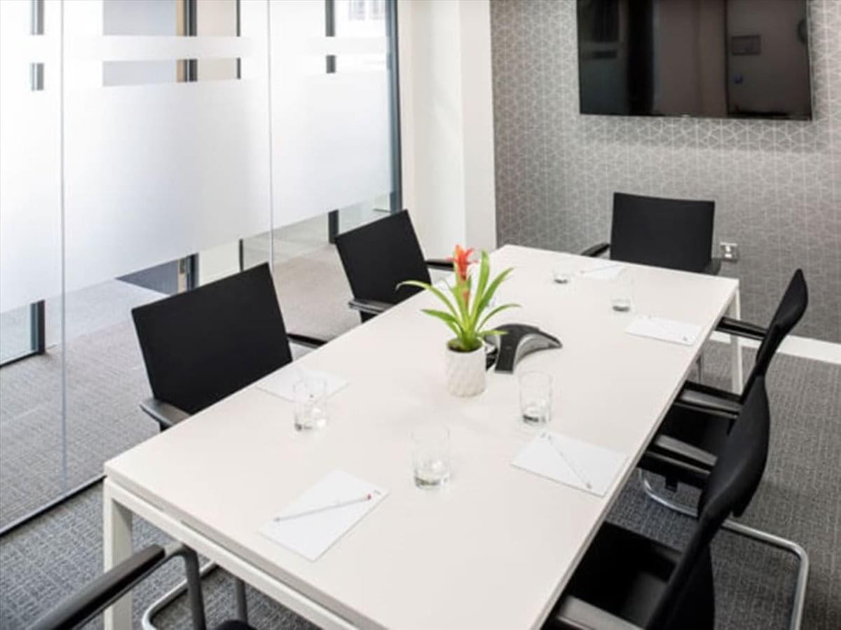Modern meeting room at Rongdu International Building featuring a white table, black chairs, and a potted plant.