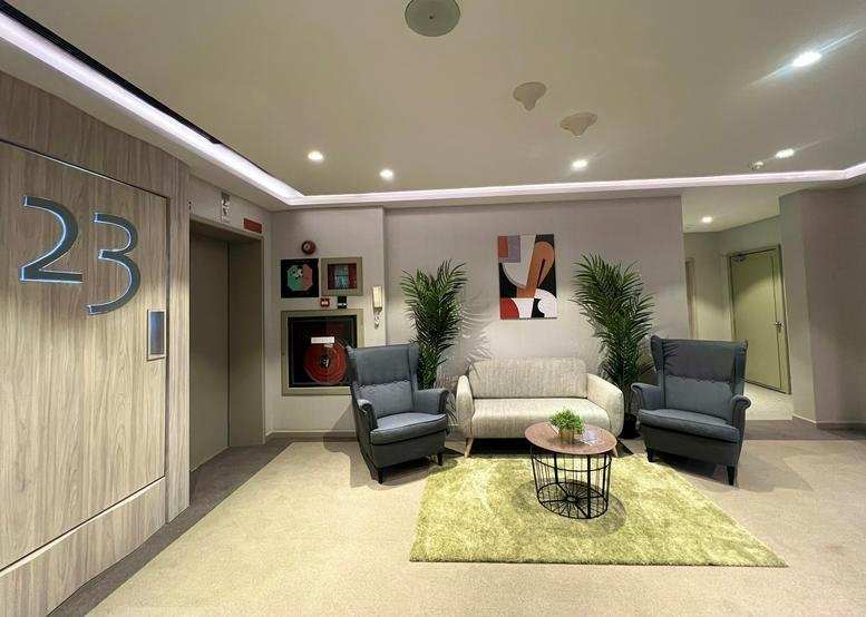 Modern reception lounge with blue wingback chairs and a green area rug.