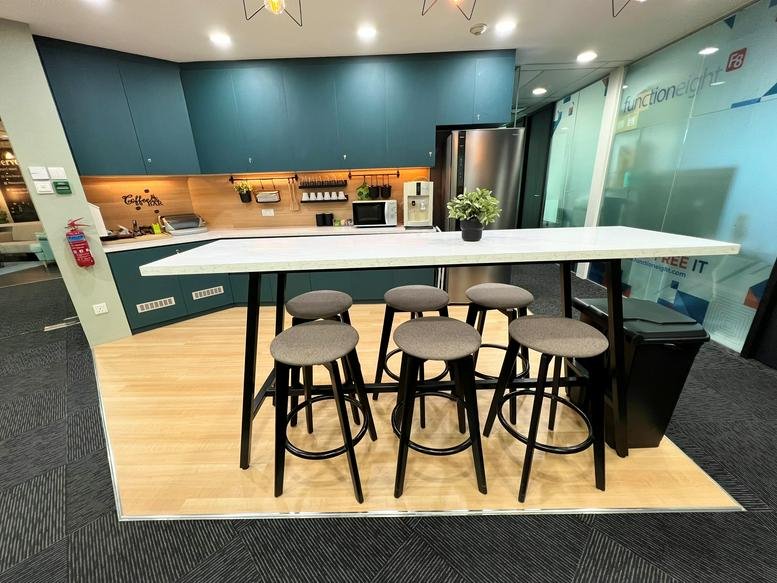 Modern pantry area featuring a high white table with grey stools and teal cabinetry.