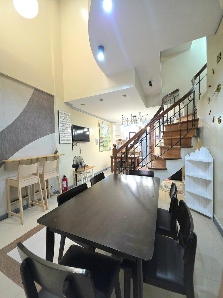 Spacious coworking area at Happy Hive Coworking Space with a large dark wood table and spiral staircase.