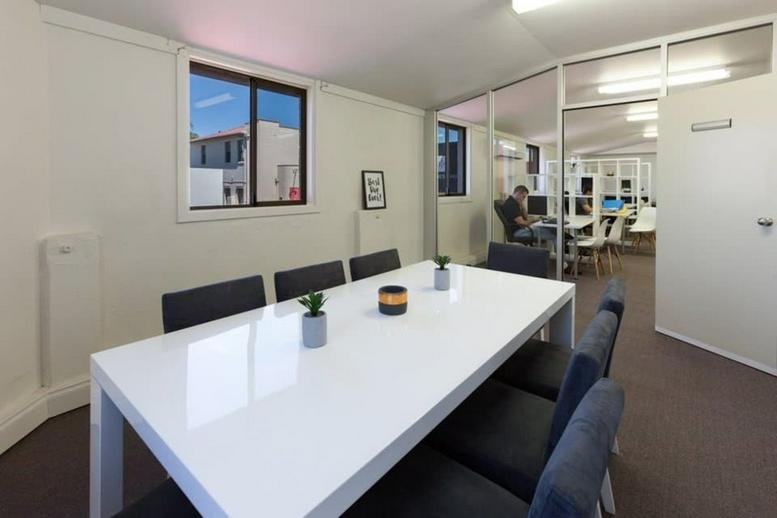 Meeting room with a white conference table, black chairs, and natural light at 110 Prospect Rd.